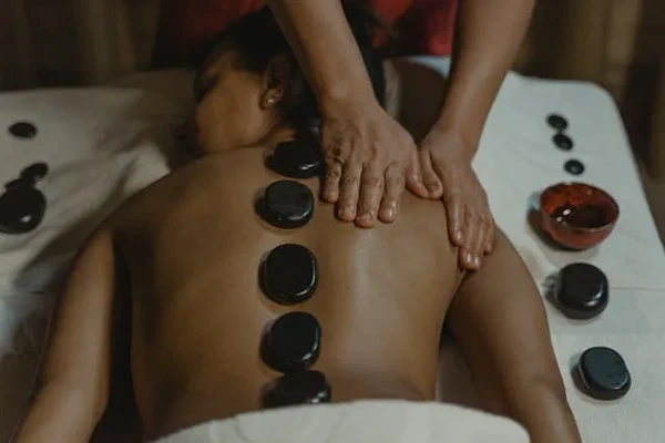 Smooth, heated volcanic stones placed along a client’s spine for deep heat muscle therapy.
