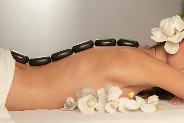Heated stone massage therapy for stress relief and blood flow in Delhi NCR.