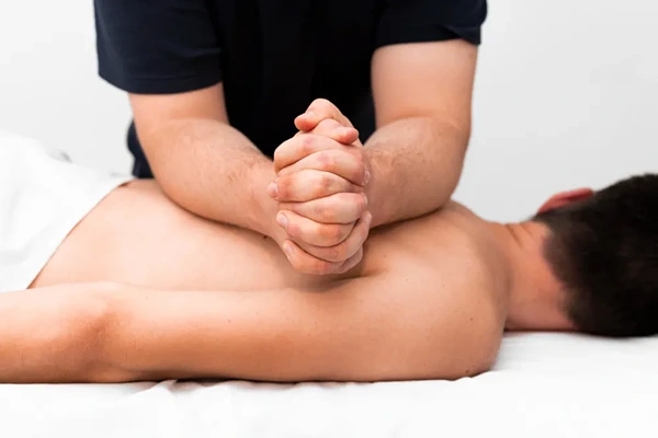 Male therapist performing sports massage for gym recovery and muscle flexibility.