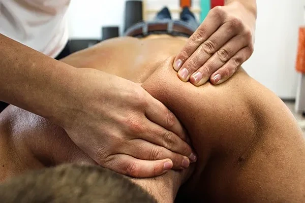 Male therapist performing assisted stretching and pressure techniques during a Thai massage session.